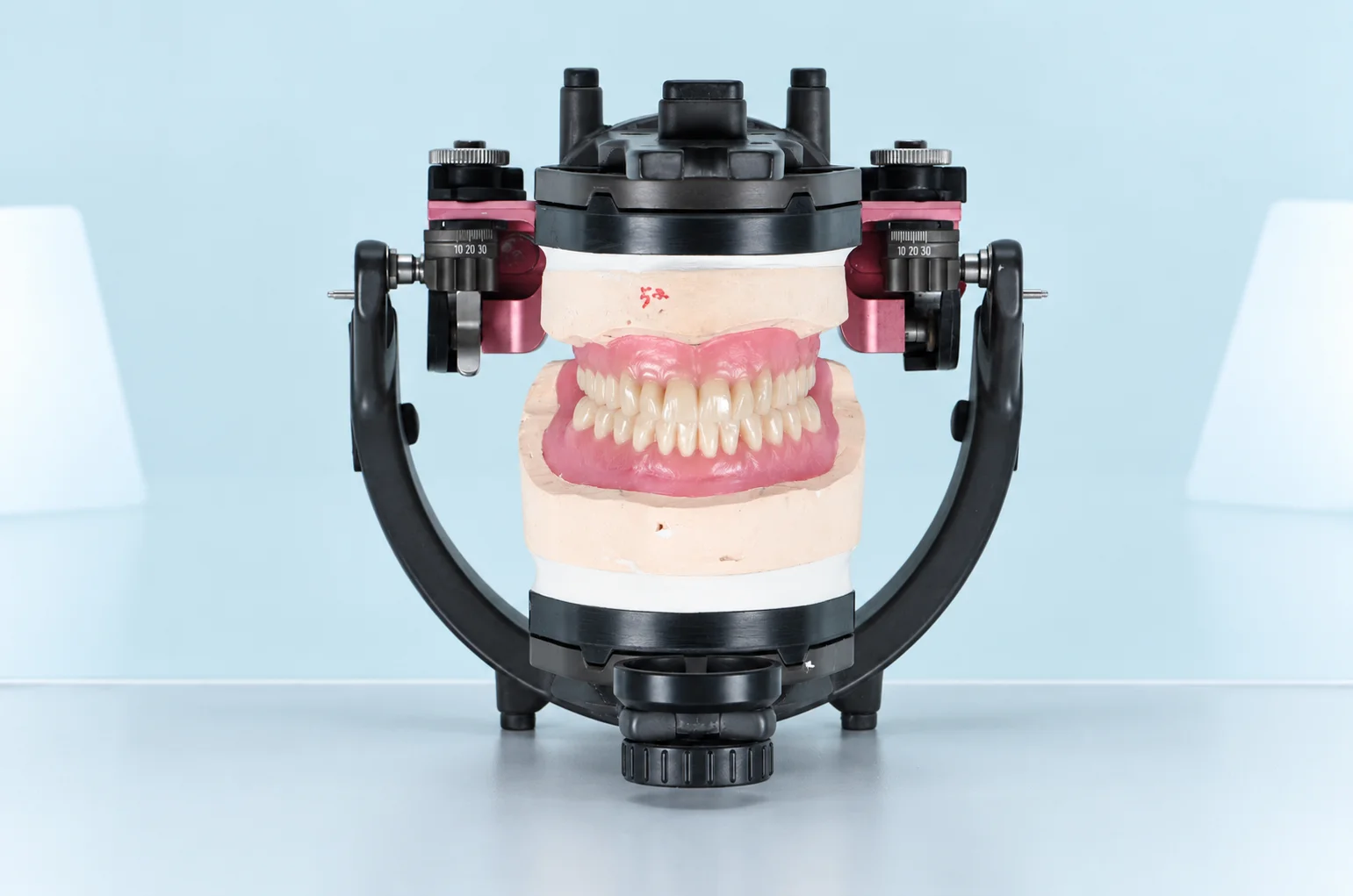 Implant-supported overdenture with attachment components displayed on a beige surface.